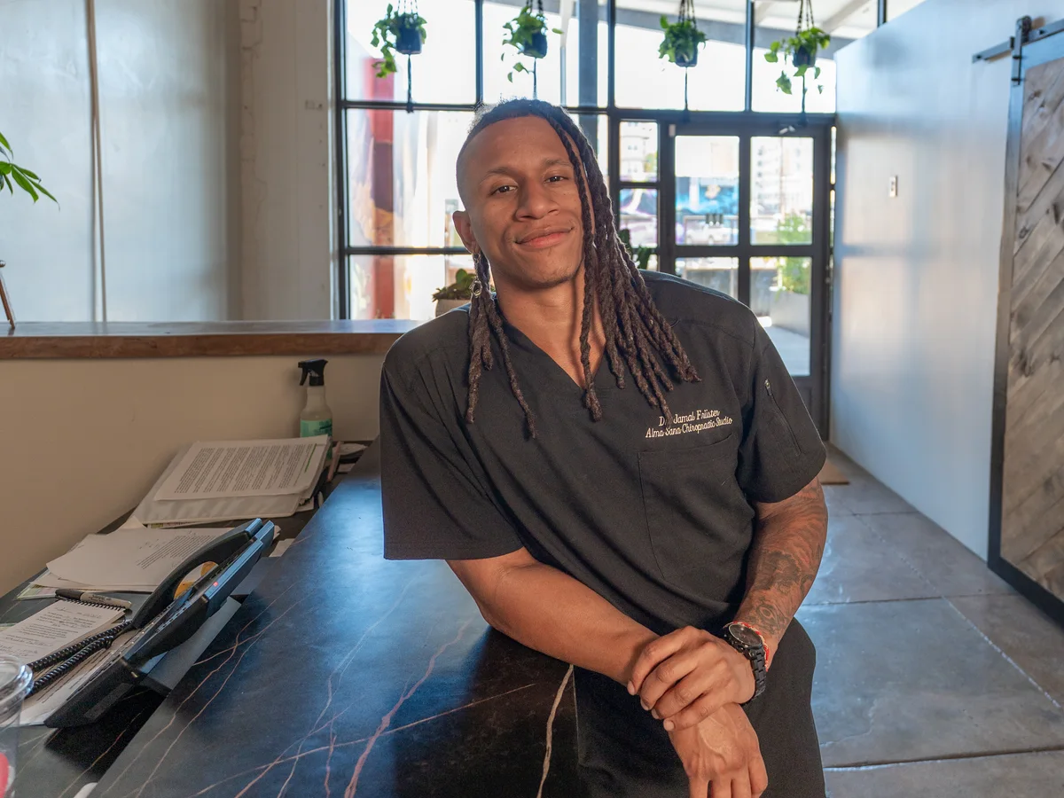 Dr. Jamal Früster welcoming patients at the front desk of Alma Sana Chiropractic Studio