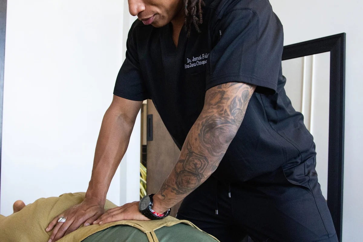 Dr. Jamal Früster delivering an adjustment to a patient lying on the treatment table