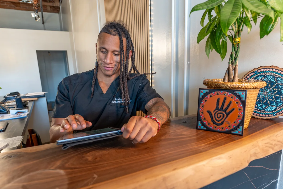 Dr. Jamal Früster at the front desk of Alma Sana Chiropractic Studio
